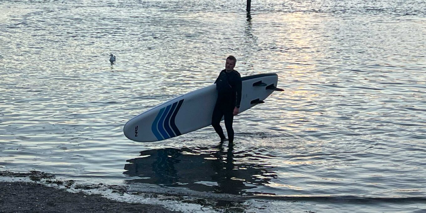 Nigel exiting the water carrying a NRS Jukdo Paddleboard