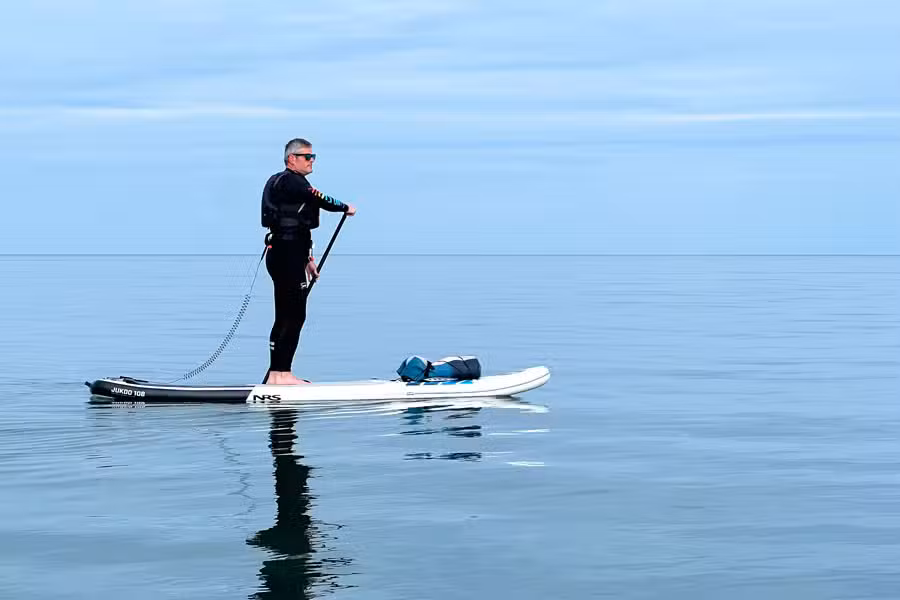 Nigel paddleboarding an NRS Jukdo inflatable paddle board on calm water