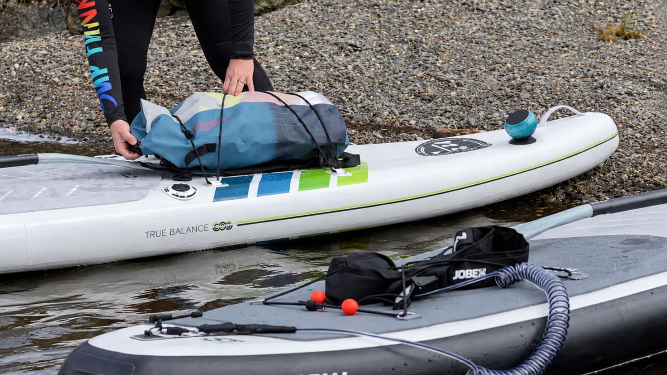 Compact waterproof speaker with paddle boarding equipment on an inflatable SUP