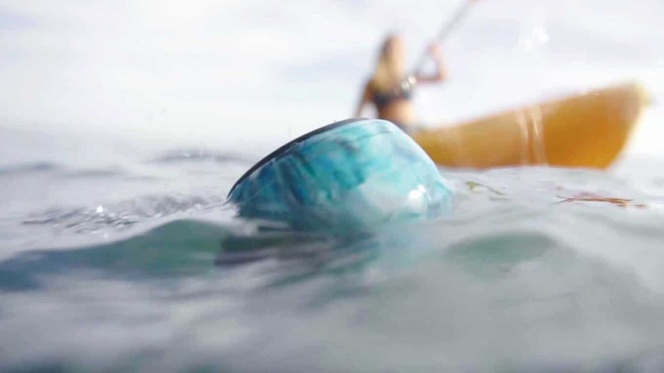 Floating waterproof Bluetooth speaker beside a out of focus kayak