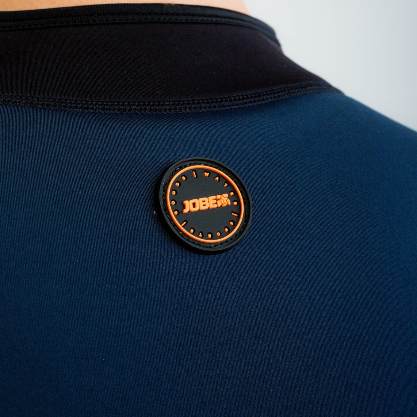 Close-up of the rear Jobe badge and flatlock seam on the Toronto 2mm men’s neoprene jacket