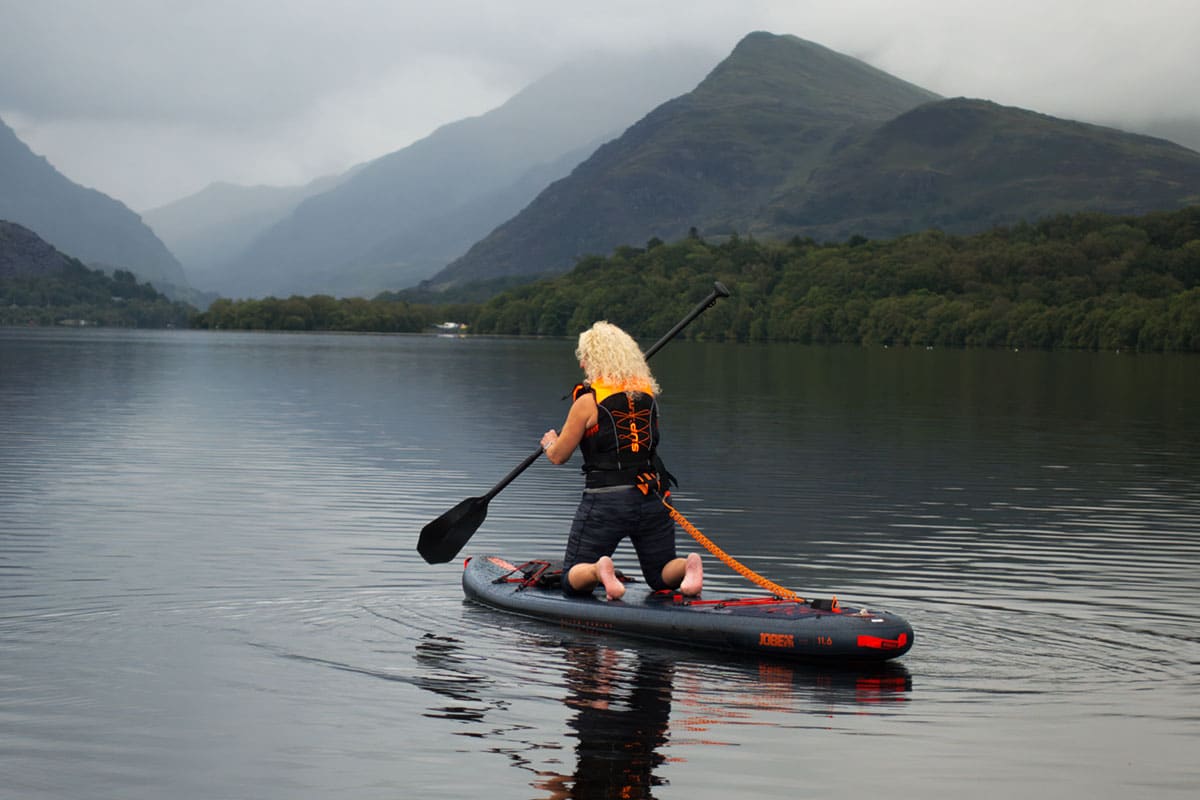 Paddleboarder wearing a buoyancy aid on a mountain lake