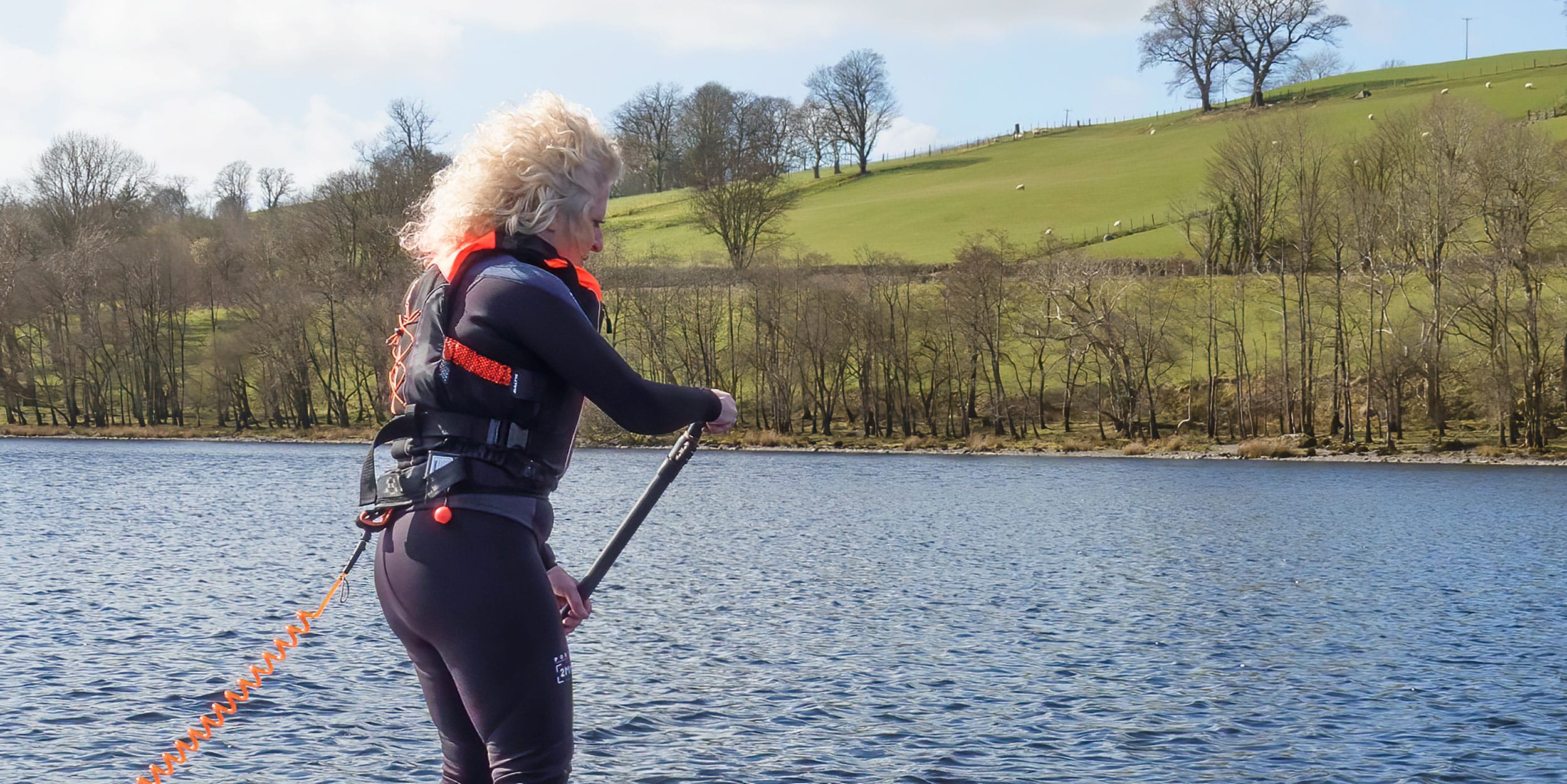 Paddle boarder wearing a buoyancy aid while paddling on a UK lake