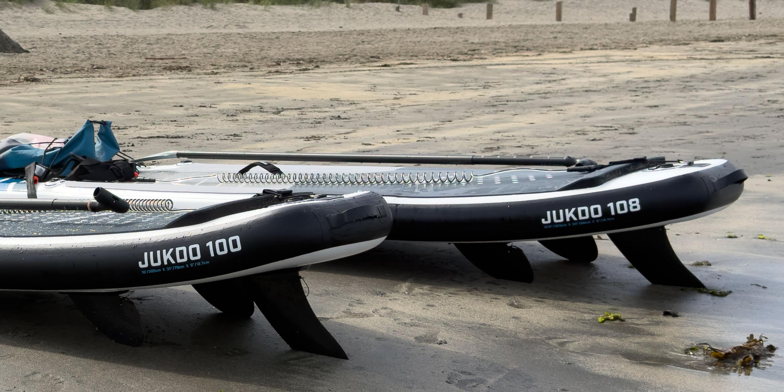 Inflatable paddle boards with fitted SUP fins on a beach