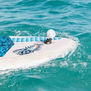 White speaker on a Speaqua Board Mount attached to the nose of a paddle board with water splashing around it