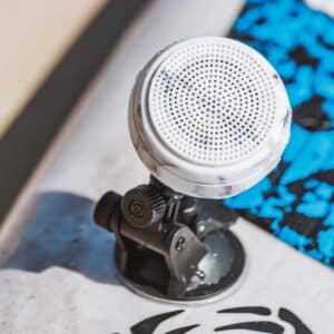 Front close-up of a white speaker on a Speaqua Board Mount beside a blue paddle board deck pad
